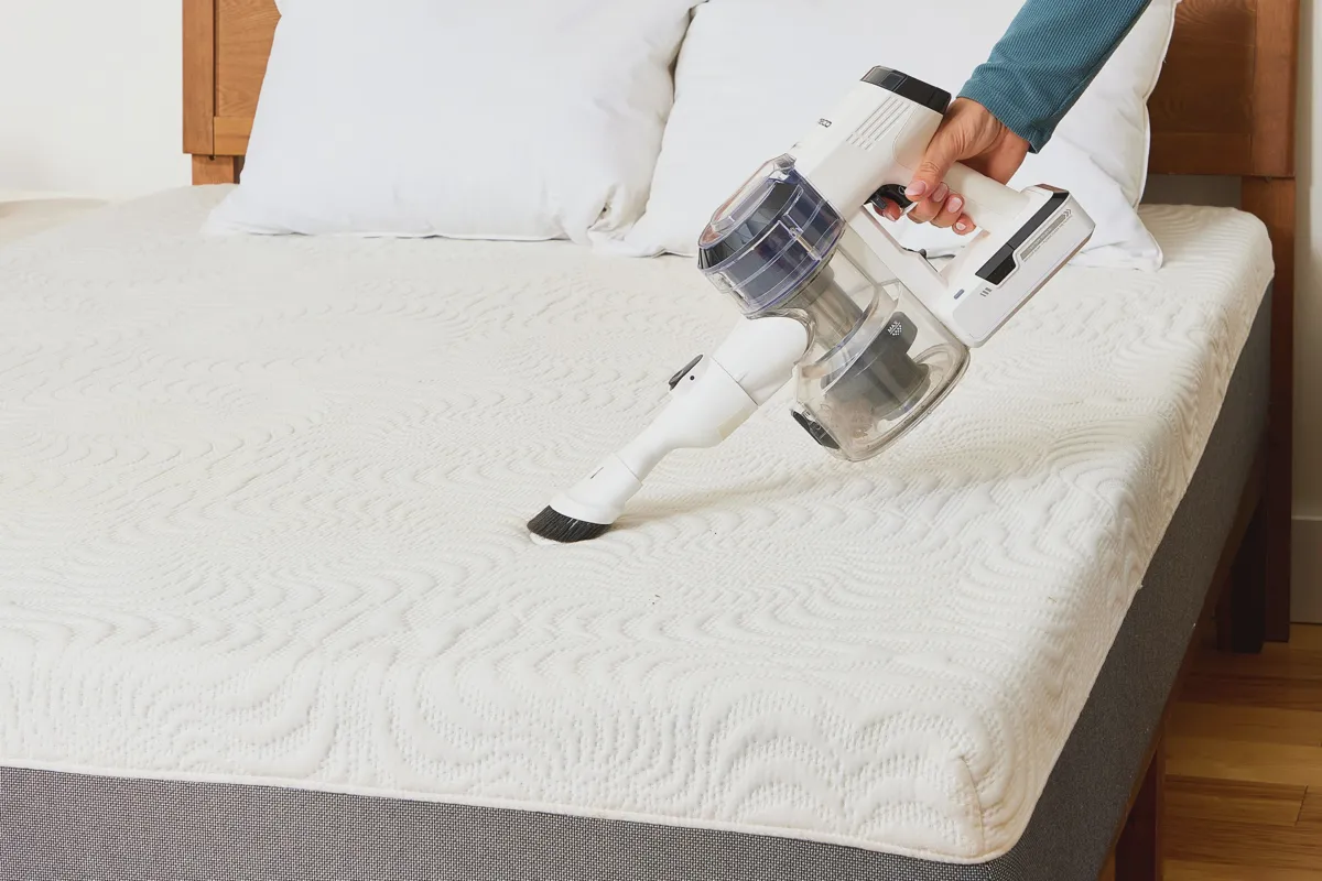 Vacuuming a bare mattress to remove debris and pheromone trails