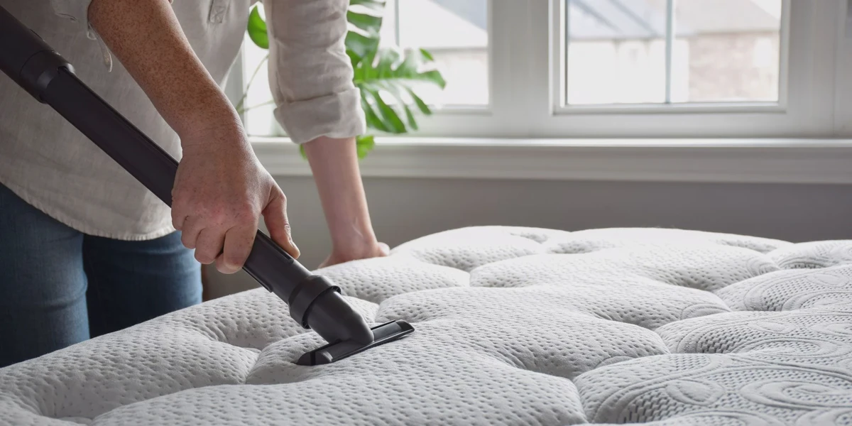 Vacuuming a mattress surface with an upholstery attachment