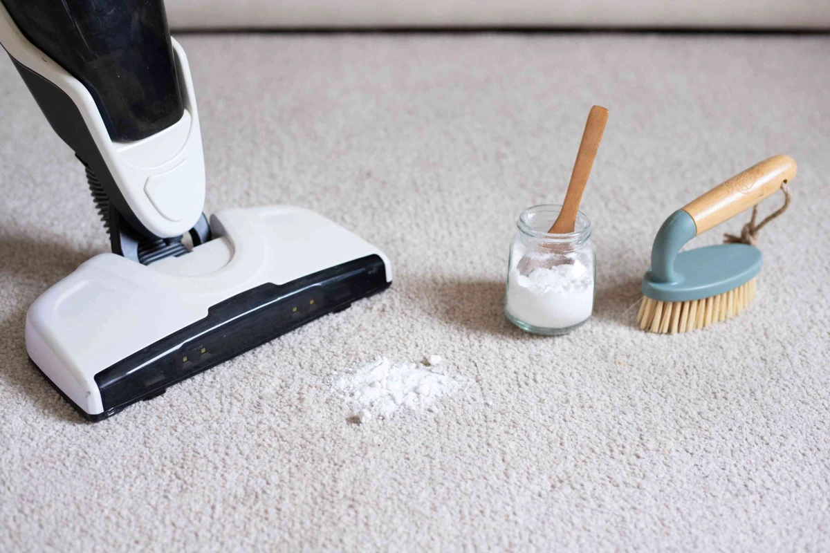 Baking soda being sprinkled from a box onto a fabric surface