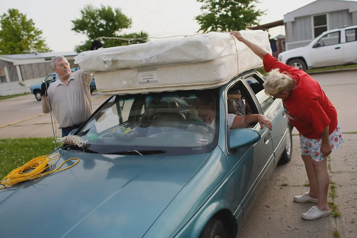 Box spring strapped to a car roof rack with ratchet straps