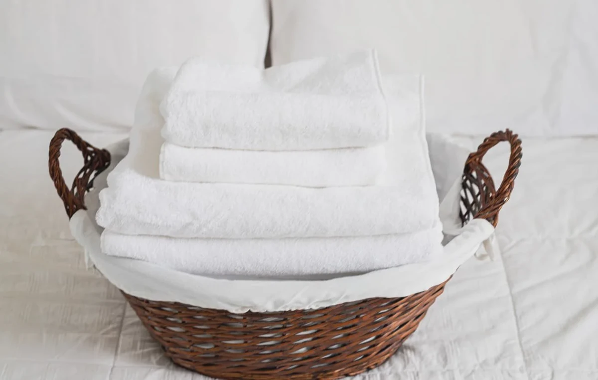 White linens in laundry basket on a bed, sorted before washing