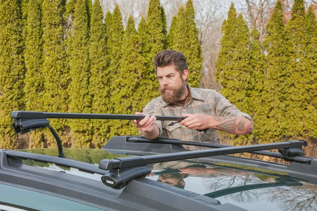 Person loading and tying cargo to a roof rack carrier