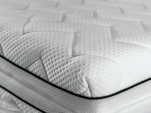 Layered mattress materials including foam, coils, and natural fiber cover