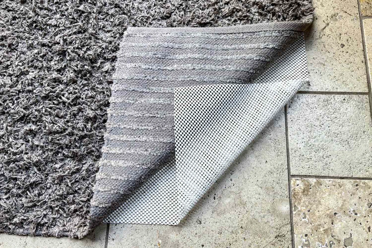 Non-slip rubberized gripper pad placed under a rug to prevent sliding