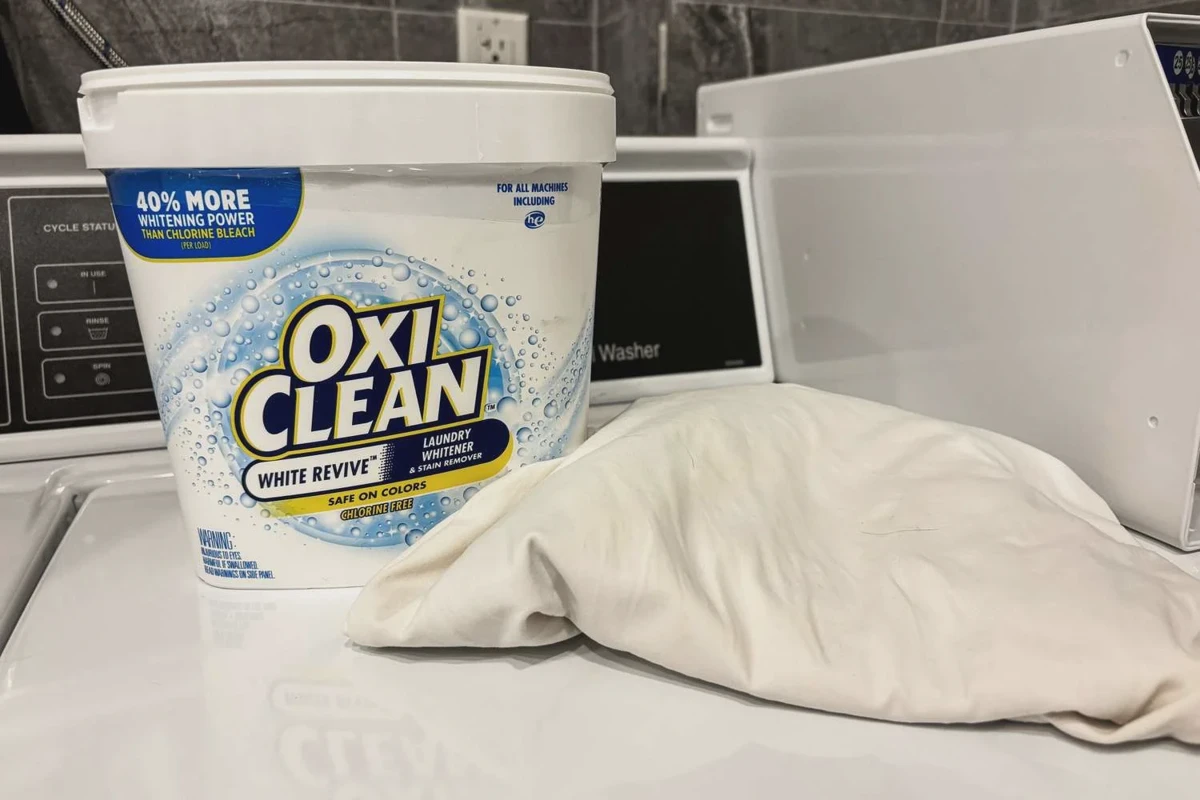 Hands applying laundry stain remover to a white pillowcase