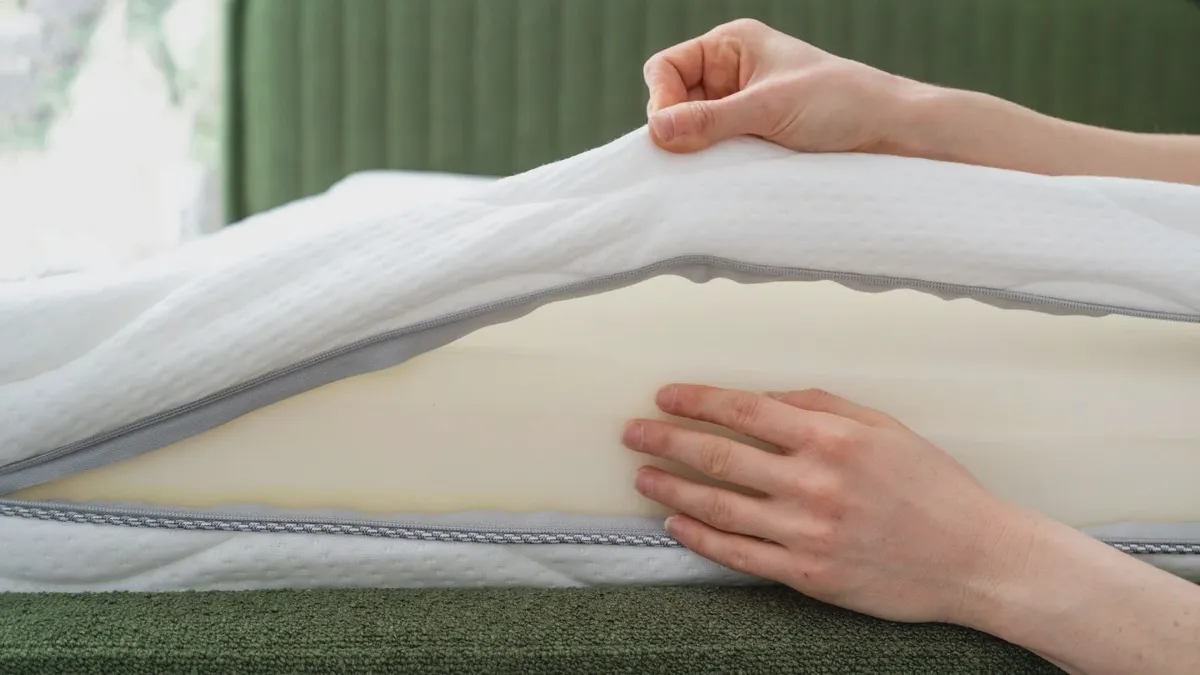 Memory foam mattress with cover partially unzipped exposing inner fire barrier