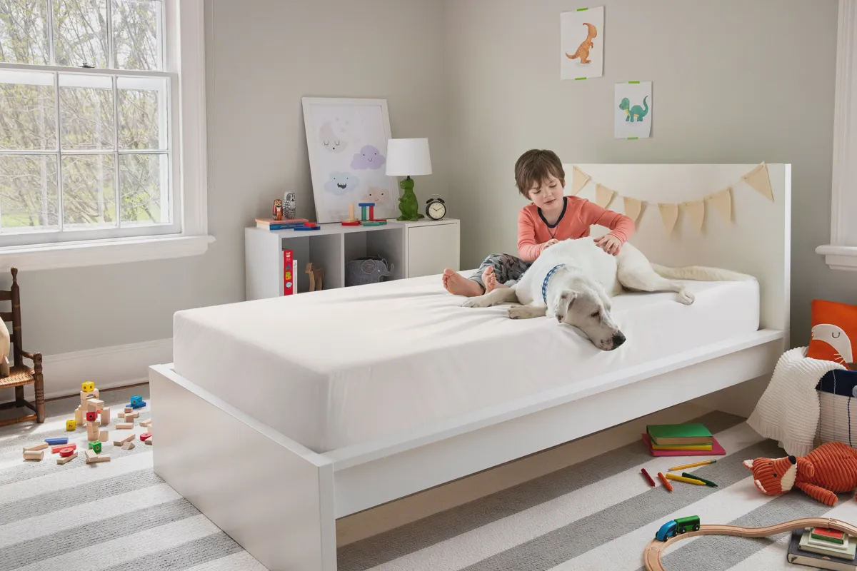 Family with kids and a dog relaxing on a mattress in a bedroom