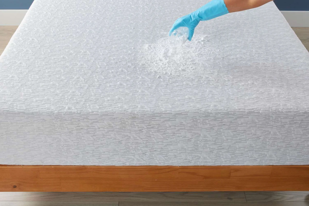 Blotting a fresh urine stain on a mattress with a white cloth