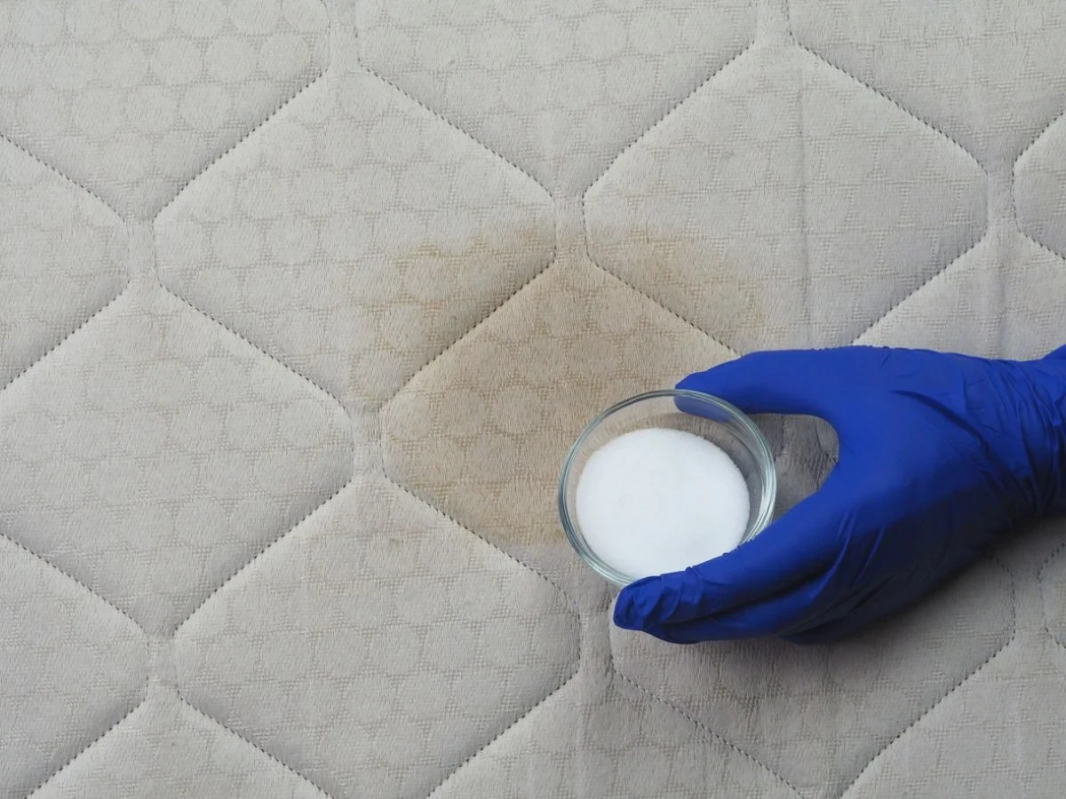 Sprinkling baking soda over a memory foam mattress to absorb moisture and odor