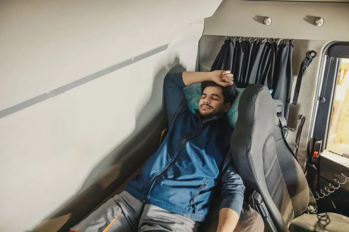 Truck driver resting in semi-truck sleeper cab