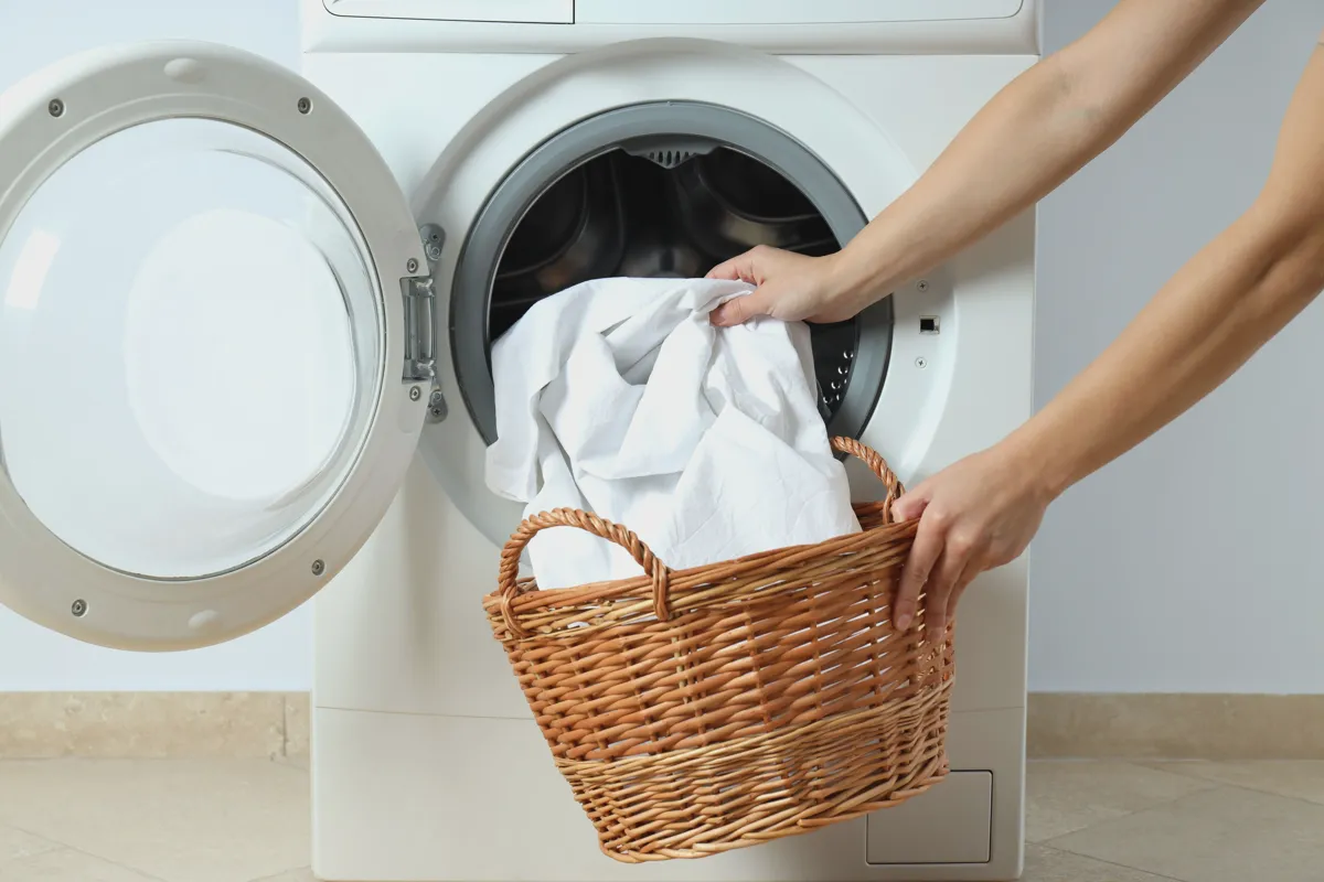 Pouring laundry detergent into a washing machine for white sheets