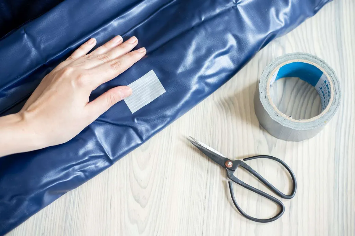 Pressing a vinyl patch firmly onto an air mattress to seal a hole