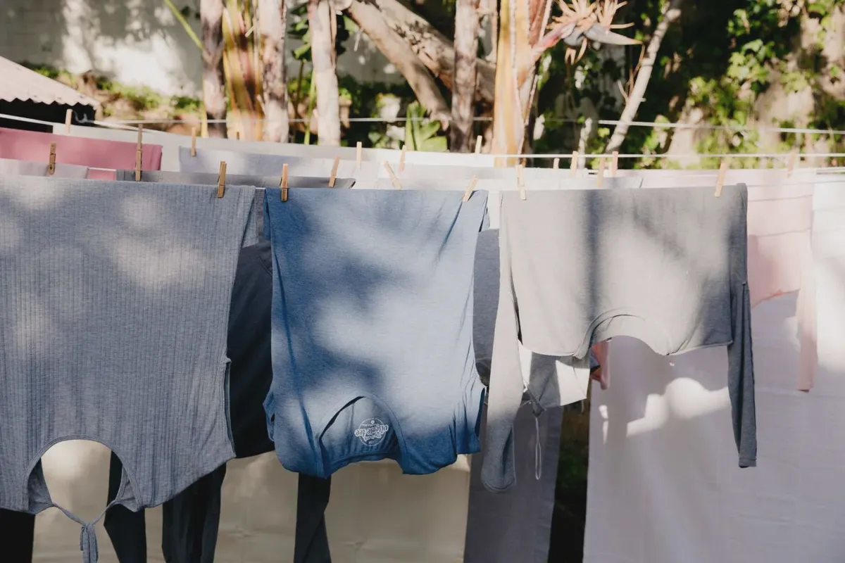 Cotton sheets and clothes air-drying on an outdoor clothesline to prevent shrinkage