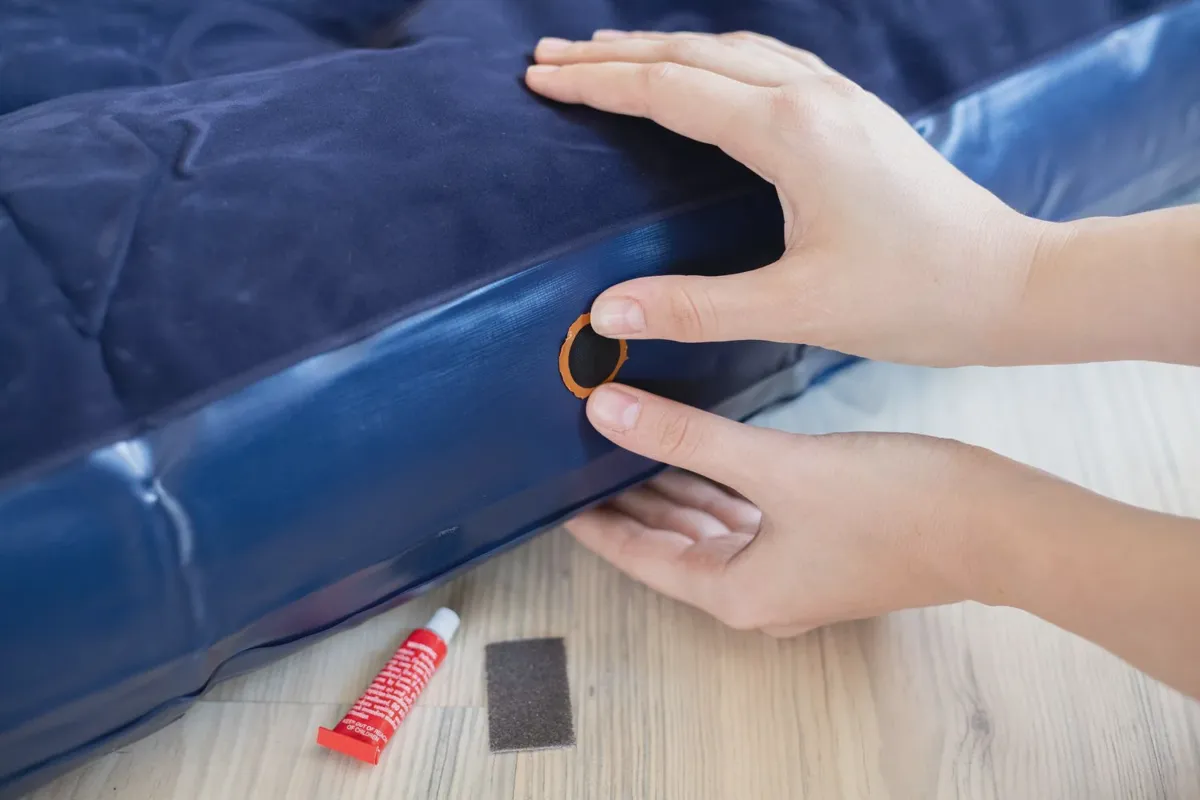 Patch kit being applied to a leak on a deflated air mattress