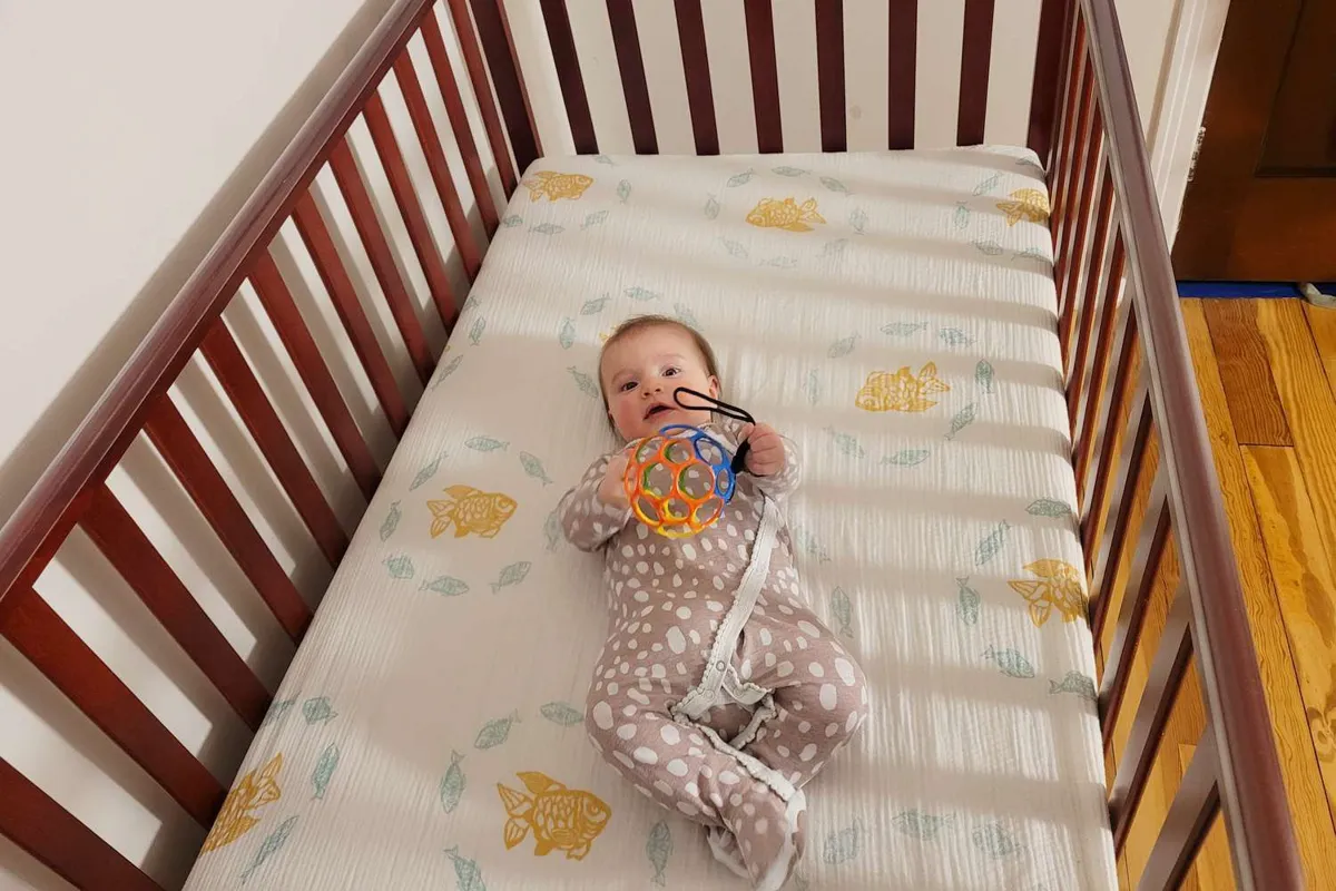 Testing the fit of a crib mattress inside a standard crib