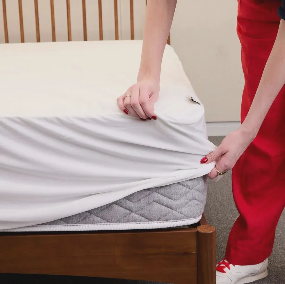 A waterproof mattress protector being fitted onto a bed to prevent future spills from soaking the mattress