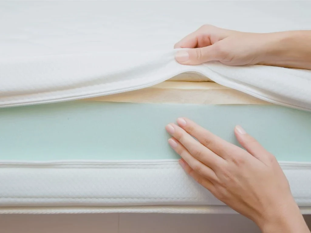 Hand inspecting the foam and cover layers of a memory foam mattress