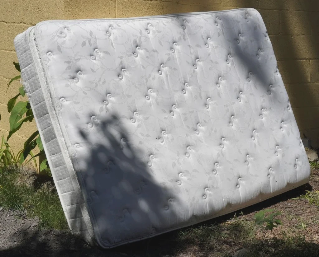 Discarded mattress left at the curb, an example of improper disposal