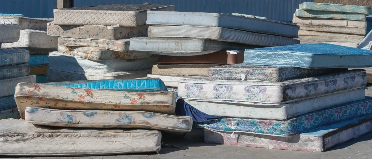 Stacks of used mattresses awaiting recycling at a sorting facility